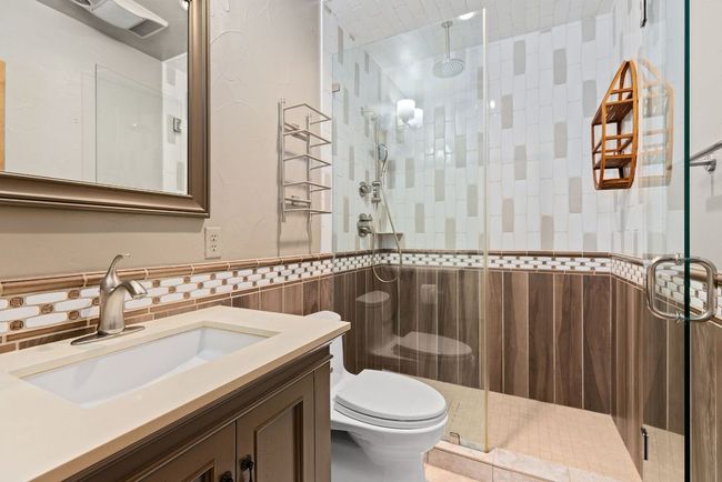 Bathroom with vanity, tile walls, a stall shower, and wainscoting | Image 21