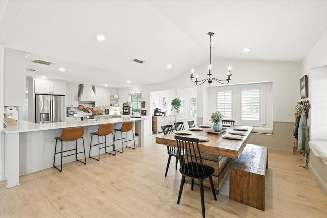 Dining space featuring a wainscoted wall, a chandelier, plenty of natural light, light wood-type flooring, and vaulted ceiling | Image 7