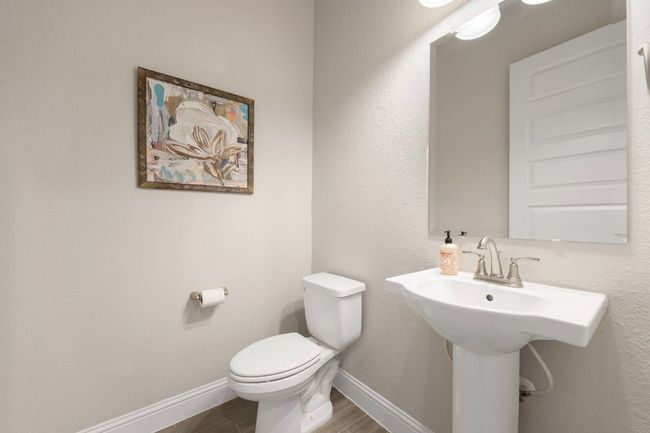 Half bathroom featuring toilet, baseboards, wood finished floors, and a sink | Image 17