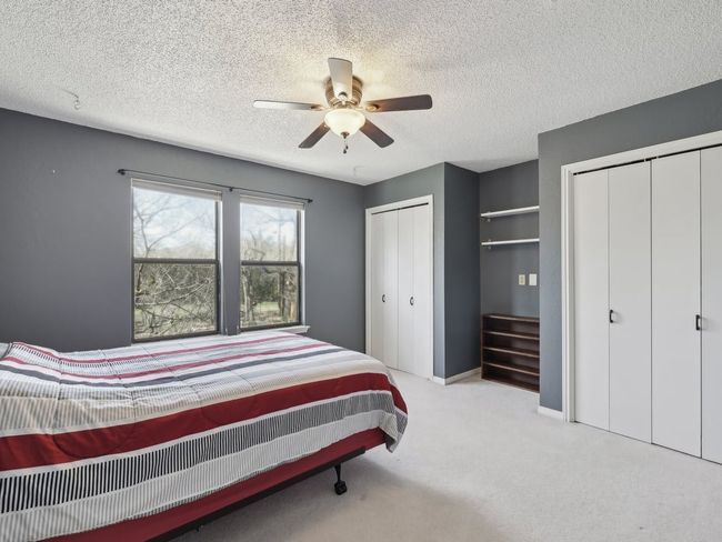 Carpeted bedroom with multiple closets, ceiling fan, baseboards, and a textured ceiling | Image 20