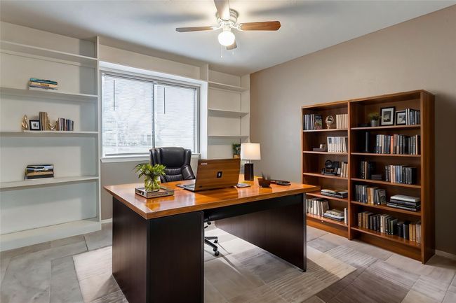 This versatile room features built-in shelving, ideal for showcasing books, collectibles, or décor. The neutral tones and updated tile flooring create a clean and modern feel. A large window floods the room with natural light, making it a perfect space for a home office, guest room, or creative studio. | Image 14