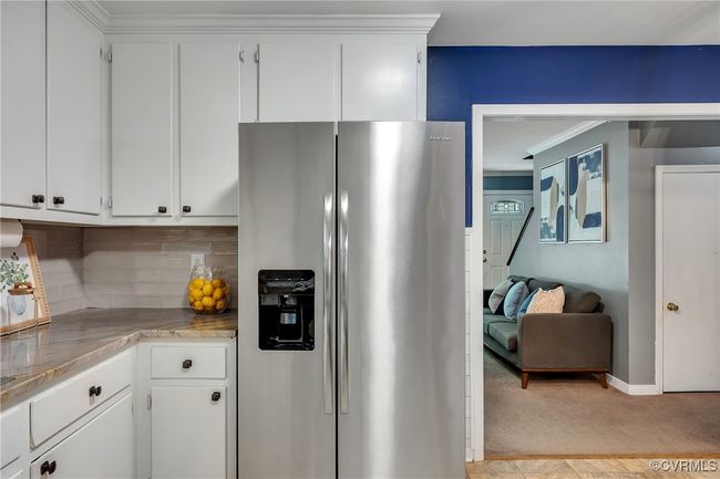 Updated eat-in kitchen with stainless steel fridge, backsplash, quartzite countertops, white cabinets, crown molding, custom built-in pantry & bar area, new lighting | Image 14