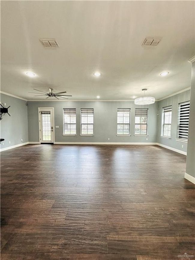 Unfurnished living room featuring ornamental molding, dark wood finished floors, recessed lighting, a ceiling fan, and a chandelier | Image 8