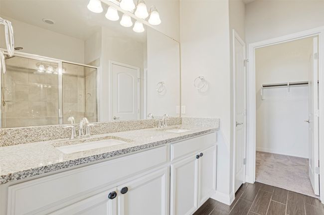 Full bathroom featuring a shower stall, wood finish floors, double vanity, and a spacious closet | Image 21