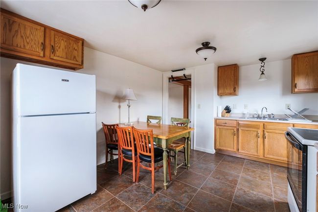 Kitchen featuring electric range, a sink, freestanding refrigerator, brown cabinetry, and light countertops | Image 31