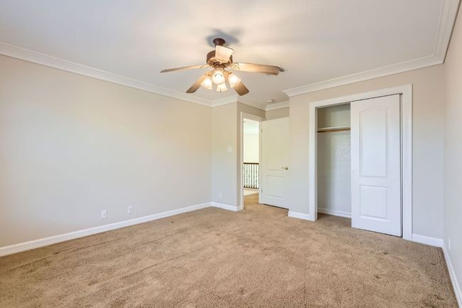 Unfurnished bedroom featuring a closet, baseboards, crown molding, ceiling fan, and carpet | Image 29