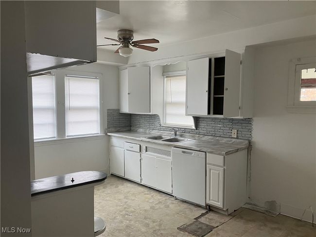 Kitchen with ceiling fan, a sink, backsplash, and white dishwasher | Image 9