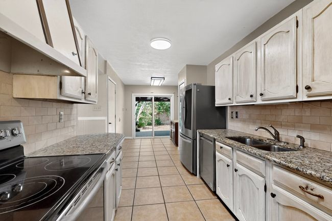 Kitchen featuring appliances with stainless steel finishes, ventilation hood, light tile patterned flooring, and backsplash | Image 9