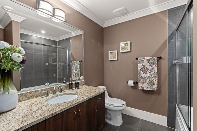 Bathroom with a tile shower, toilet, vanity, tile patterned flooring, and visible vents | Image 27