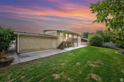 Back house at dusk with a patio area and a lawn | Image 3