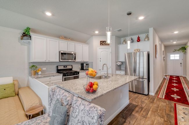 Kitchen featuring stainless steel appliances, a sink, backsplash, and white cabinetry | Image 12