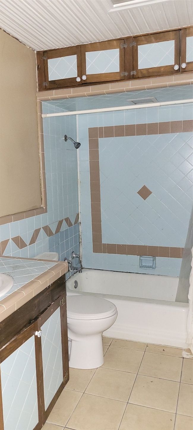 Full bath featuring shower / bath combo, tile patterned flooring, vanity, tile walls, and tasteful backsplash | Image 16