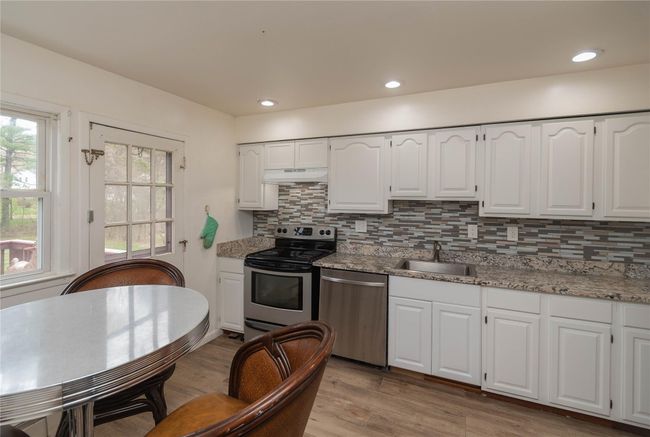 Kitchen wih white wood cabinets, decorative backsplash, stainless steel appliances | Image 6
