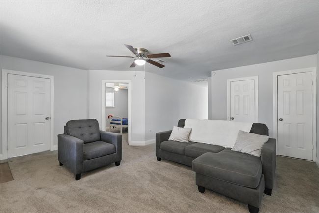 Living room featuring ceiling fan, light carpet, baseboards, and a textured ceiling | Image 24