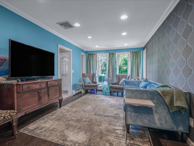Living area with ornamental molding, dark wood-style floors, recessed lighting, wallpapered walls, and baseboards | Image 5