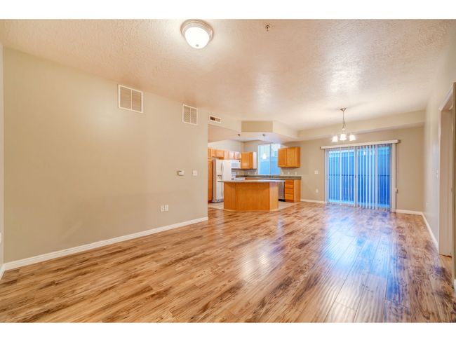 Unfurnished living room with a chandelier, light wood finished floors, a textured ceiling, and baseboards | Image 11