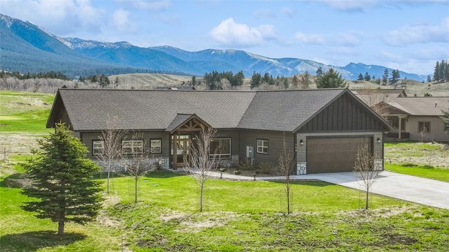Rustic home with board and batten siding, a front yard, an attached garage, a mountain view, and driveway | Image 43