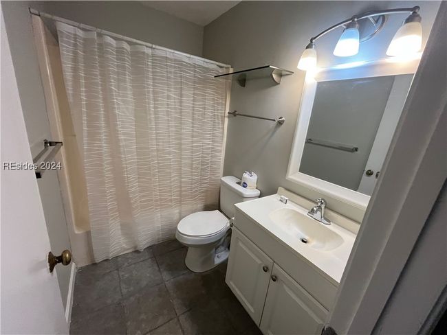 Full bathroom with vanity, toilet, shower / bath combination with curtain, and tile patterned flooring | Image 6