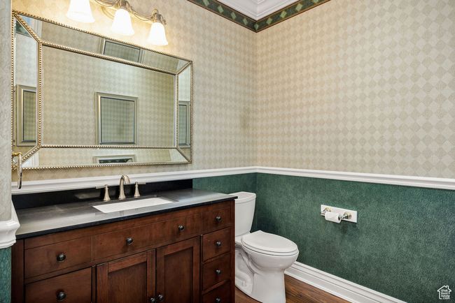 Bathroom with wood finished floors, toilet, vanity, and wallpapered walls | Image 24