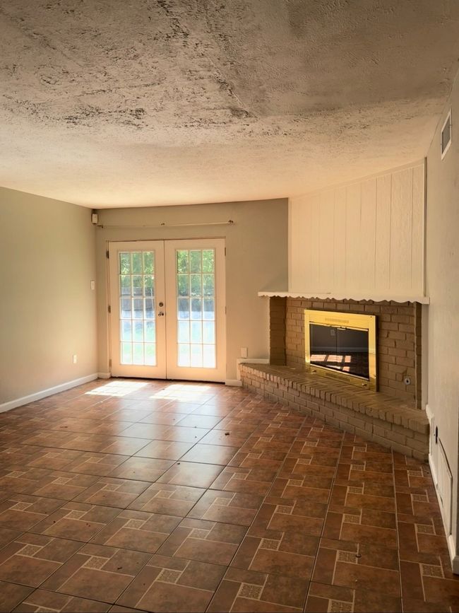 Unfurnished living room featuring french doors, a textured ceiling, and a fireplace | Image 4