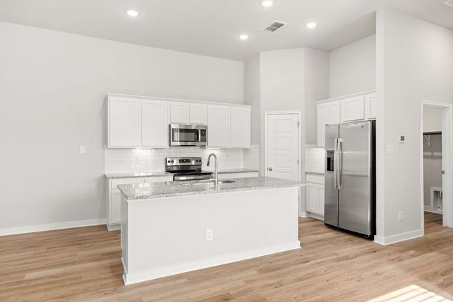 Kitchen featuring stainless steel appliances, a sink, a kitchen island with sink, and white cabinets | Image 14
