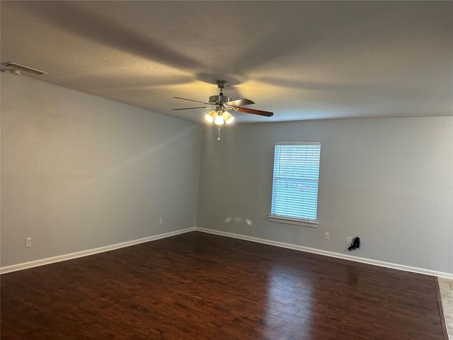 Spare room with baseboards, dark wood-style flooring, visible vents, and a ceiling fan | Image 5