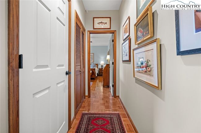 Hallway leading to the primary bedroom. Louvered doors house the stack washer and dryer | Image 23