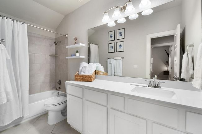 Upstairs full bath featuring vaulted ceiling, tile patterned floors, vanity, shower / bathtub combination with curtain, and toilet | Image 30