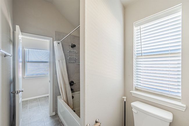 Full bath featuring toilet, tile patterned flooring, shower / tub combo, and vaulted ceiling | Image 33
