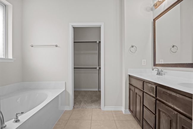 Full bathroom with double vanity, a walk in closet, a bath, tile patterned floors, and a sink | Image 22