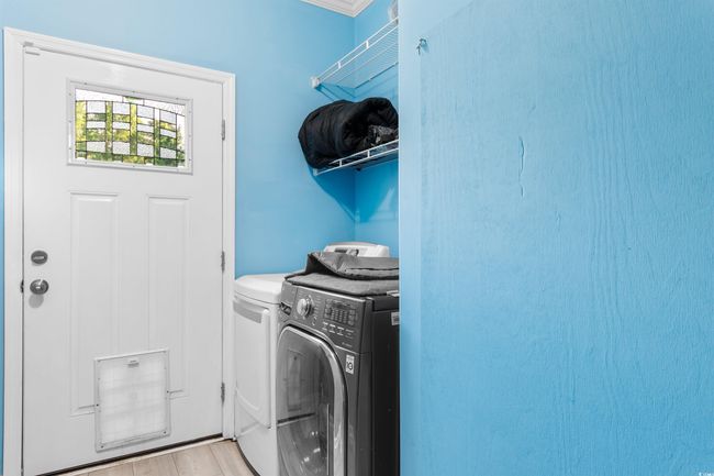 Laundry area featuring washing machine and dryer and wood finished floors | Image 24