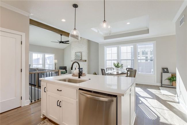 Kitchen with decorative light fixtures, light wood-style floors, visible vents, dishwasher, and a sink | Image 13