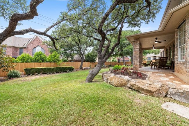 Expansive backyard retreat with shaded trees, stone accents, and a generous covered patio—ideal for relaxing or entertaining outdoors. | Image 32