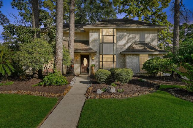 Charming two-story home with a welcoming entrance, set amidst mature trees and lush landscaping. The well-maintained exterior features large windows for plenty of natural light. Ideal for those seeking a peaceful, nature-inspired setting. | Image 8