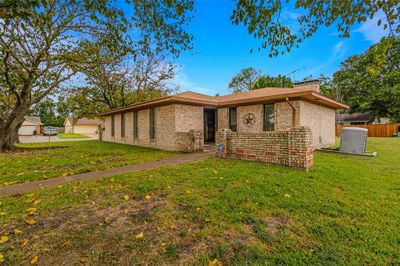 Ranch-style home with a front yard and central AC | Image 1