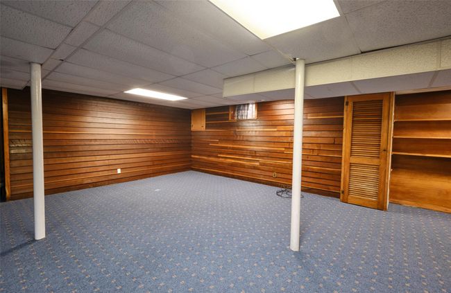 Finished basement featuring a drop ceiling, carpet flooring, and wooden walls | Image 14