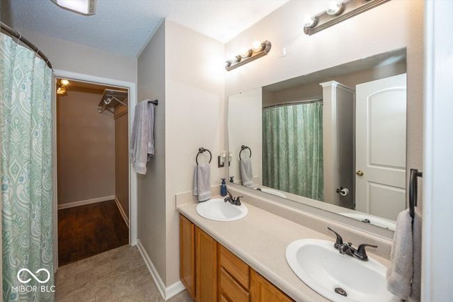 full bath with a walk in closet, baseboards, a sink, and double vanity | Image 18