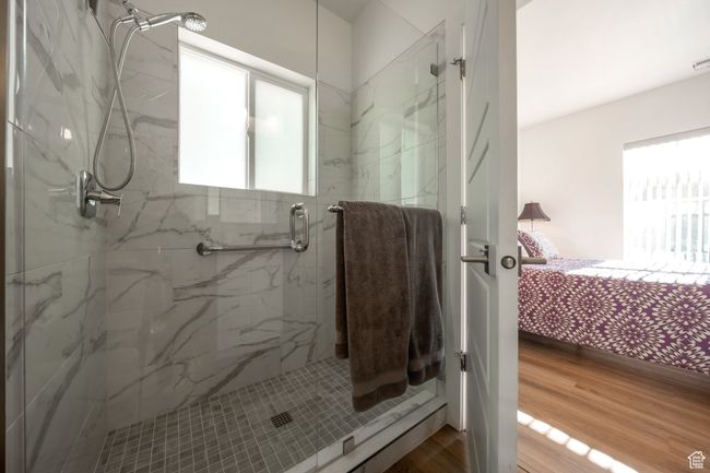 Full bathroom featuring healthy amount of natural light, a marble finish shower, ensuite bathroom, and wood finished floors | Image 10