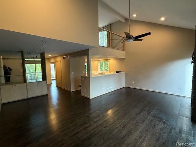 Unfurnished living room with ceiling fan, dark wood finished floors, high vaulted ceiling, beamed ceiling, and recessed lighting | Image 10