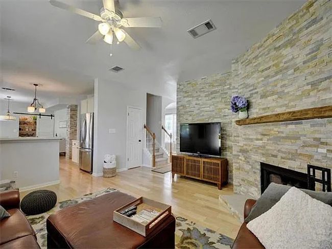 Living area featuring a ceiling fan, a stone fireplace, light wood-type flooring, and stairway | Image 8