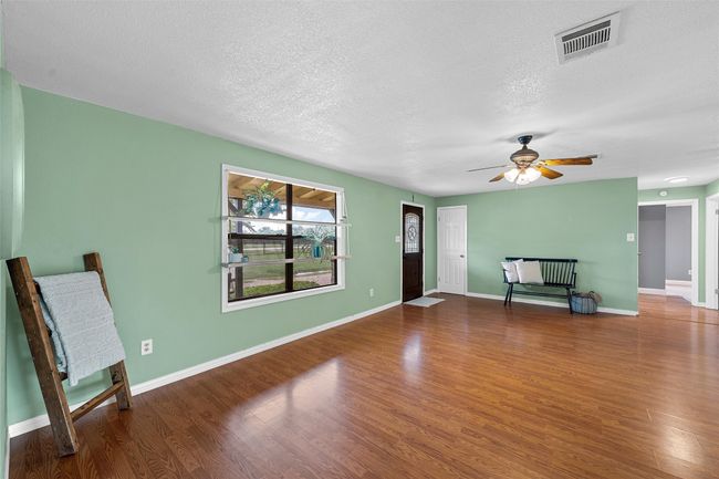 Unfurnished living room featuring a textured ceiling, wood finished floors, and a ceiling fan | Image 6