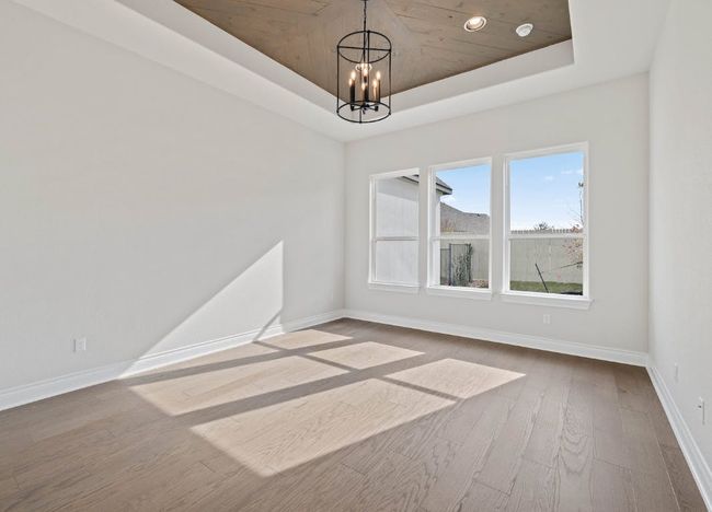 Unfurnished dining area featuring baseboards, a raised ceiling, a notable chandelier, and wood finished floors | Image 17