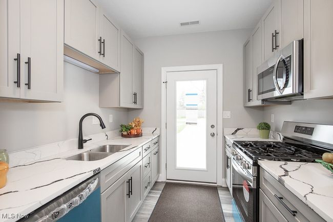 Kitchen with plenty of natural light, sink, stainless steel appliances, and light stone countertops | Image 15