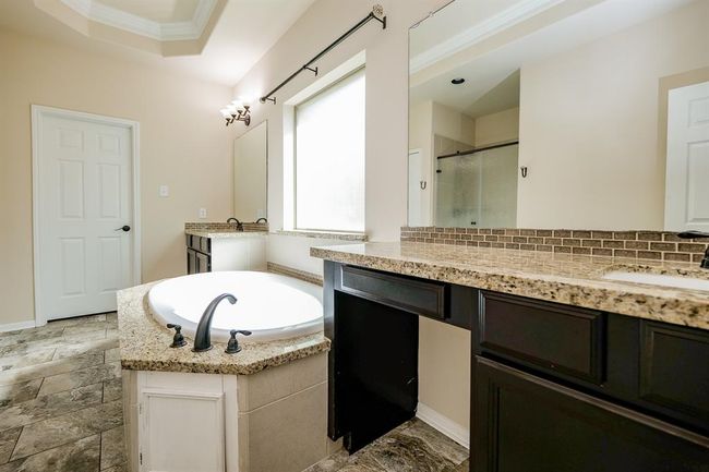 Contemporary simplicity is the key to casual elegance in your primary ensuite bath; with warm tray ceiling, soothing walls and beautiful tile flooring; dual/separate sinks/vanity set into striking caramel colored granite counter tops, with rich dark cabinetry below and simple wall-wide mirrors, above. The huge frosted glass window makes bathing completely private! | Image 28