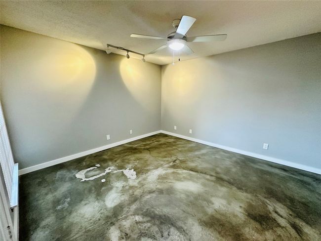 Spare room with rail lighting, unfinished concrete flooring, a textured ceiling, and a ceiling fan | Image 11