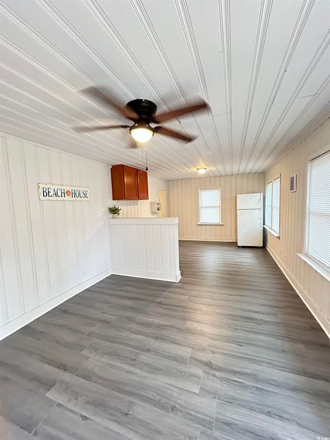 Unfurnished living room with ceiling fan, dark wood finished floors, and wooden walls | Image 5