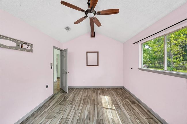 Experience tranquility in this spacious primary bedroom, featuring elegant flooring, abundant natural light, and a stylish ceiling fan for ultimate comfort. | Image 23