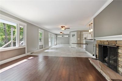 Unfurnished living room with ceiling fan, a fireplace, wood-style floors, and ornamental molding | Image 2