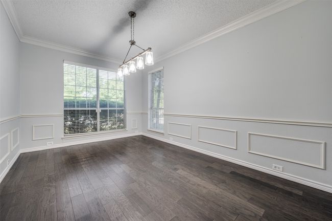 Unfurnished dining area with dark wood-type flooring, a textured ceiling, crown molding, and wainscoting | Image 14