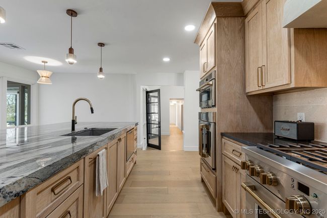 Main kitchen with luxury counters, luxury appliances, bar seating, and custom cabinets | Image 23